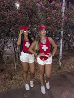 two women in red shirts and white shorts standing next to each other