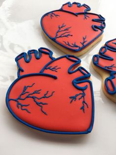 three decorated cookies with blue and red icing on top of a white tablecloth