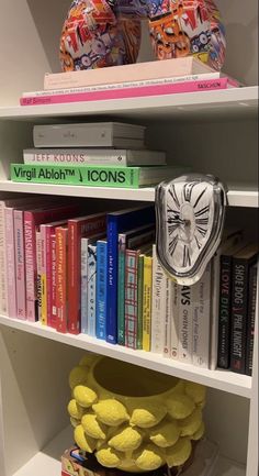 a book shelf filled with lots of books and a clock on top of one of the shelves