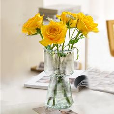 yellow roses in a glass vase on a desk