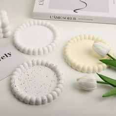 three pieces of white plastic sitting on top of a table next to tulips