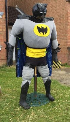 an inflatable batman statue is standing on the grass