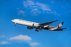 an air new zealand airplane flying in the sky with clouds behind it and blue skies above