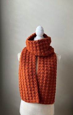 an orange crocheted scarf on top of a mannequin