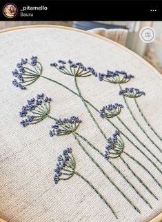 a close up of a cross stitch pattern with lavender flowers on the front and back