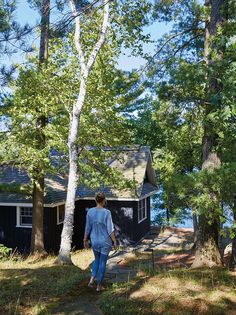 a woman walking towards a cabin in the woods