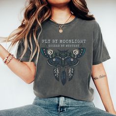 This Luna Moth Comfort Colors Cotton T-Shirt is perfect for those who love celestial and mystical designs. Featuring a wildflower celestial cottagecore design, this shirt gives off a witchy cute boho vibe. It is ideal for those who enjoy a unique and whimsical style. Perfect for wearing casually or for adding a touch of magic to your semi-formal outfits. Great for those who celebrate nature, the moon phases, and all things mystical.   Our custom apparel is designed for ultimate comfort with soft Mystical Cotton Crew Neck T-shirt, Mystical Crew Neck Cotton T-shirt, Mystical Style Cotton T-shirt With Crew Neck, Mystical Style Cotton Crew Neck T-shirt, Mystical Short Sleeve Top With Graphic Print, Mystical Graphic Print Short Sleeve Top, Mystical Graphic Print Cotton Tops, Mystical Cotton Tops With Graphic Print, Mystical Graphic Print Crew Neck Top