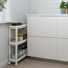 a kitchen with white cupboards and shelves filled with food, plants and other items