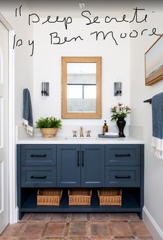 a bathroom with blue cabinets and two baskets on the counter top, mirror above it