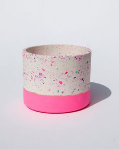 a white and pink bowl with sprinkles on the outside, in front of a white background