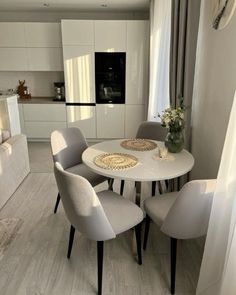 a white table with four chairs around it in a living room next to a couch