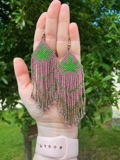 "Welcome to my big old beaded earring sale! This pair features design with a green marijuana leaf against a dark purple tinted cocoa background. The fringe is extra long with twisted bugle beads and Czech glass drops at the bottom. The beads hang from a base metal gold plated earwire. They are approximately 4 1/2\"  in total length, but only 3 1/2\" from the top of the brass. All of the beads are stitched with white nylon. Nylon holds up well to moisture, however it is strongly recommended to remove them before swimming, showering, and sleeping. The earring hook is silver plated base metal. These boho earrings ship for free in the US. If you are ordering these as a gift for someone else, I will include a handwritten note for the recipient. Just send me a note with your gift message! If you Cocoa Background, Beaded Earring, Le Crochet, Beading Projects, Bugle Beads, Earrings Long, Boho Festival, Earring Sale, Leaf Earrings