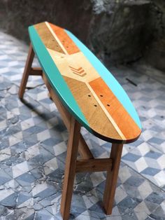 a small wooden surfboard sitting on top of a table next to a stone wall