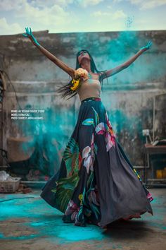 a woman in a long dress with her arms spread out and hands outstretched, standing on the ground