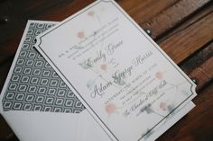 two wedding cards sitting on top of a wooden bench next to an envelope with flowers