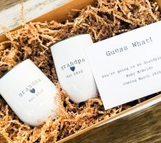 two coffee mugs sitting in a box on top of wood