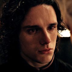 a close up of a person wearing a black shirt with long curly hair and an intense look on his face