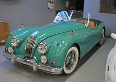 an old green car is parked in a garage