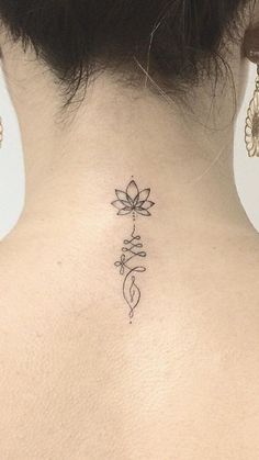 the back of a woman's neck with a flower tattoo on it