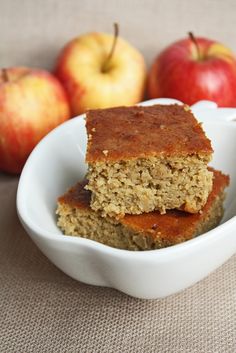 two pieces of cake in a white bowl next to apples