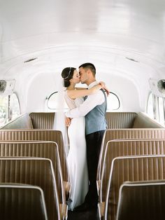 a bride and groom kissing in the back of a bus with seats on both sides