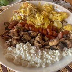 a white plate topped with eggs, sausage and rice next to other foods on a table