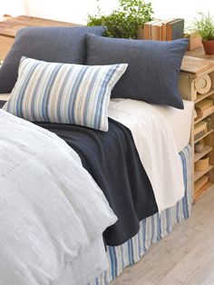 a bed with blue and white pillows on top of it next to a wooden crate