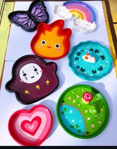 colorful plates with different designs on them sitting on a white table top next to a butterfly