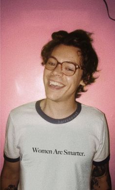 a young man with glasses smiling in front of a pink wall wearing a t - shirt that says women are smarter