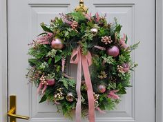 a wreath with pink and green decorations hanging on a door