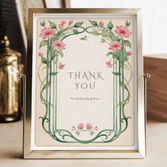 a thank you card with pink flowers in a frame on a table next to gold vases