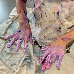 two hands covered in paint sitting on top of a table