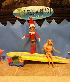 two dolls are sitting on surfboards in front of a life's a beach sign