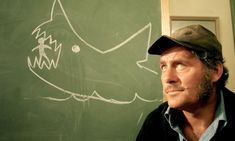 a man standing in front of a chalkboard with a shark drawn on it's side