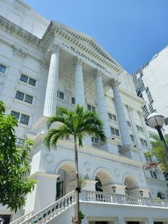 a tall white building with columns and palm trees