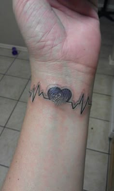 a person's wrist with a heart and heartbeat tattoo on the left side of their arm