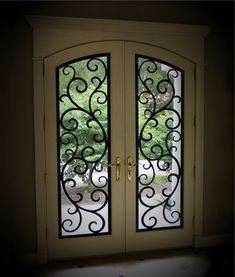 an open double door with wrought iron work on the sides and glass panels above it