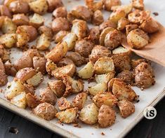 cooked potatoes on a baking sheet with a wooden spoon