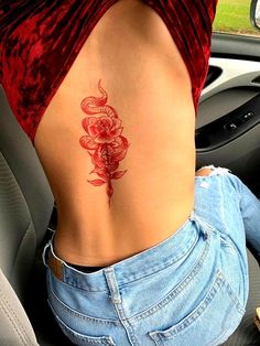 the back of a woman's stomach with a snake and flowers tattoo on it