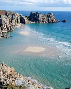 an aerial view of the beach and ocean from above, with rocks in the foreground