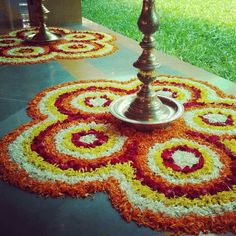 an elaborate flower arrangement on the ground in front of a building with two candles lit