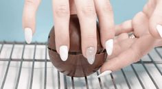 a woman's hands with white nails holding an egg