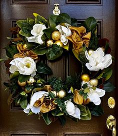 a wreath with white and yellow flowers on the front door