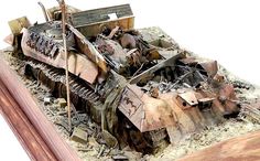 a toy model of a destroyed tank in the sand with wooden frame on white background