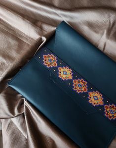 a blue purse with beading on it laying on a bed