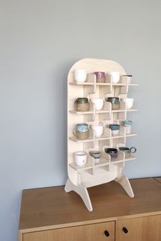 a white shelf with cups and bowls on it in front of a wall mounted cabinet