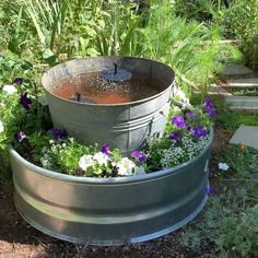 an outdoor fountain surrounded by plants and flowers