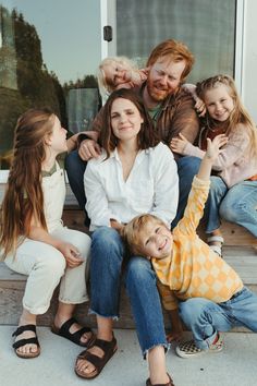 a group of people sitting on top of each other in front of a door with their arms up