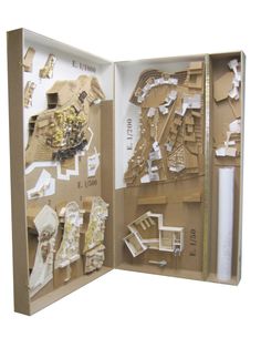 an open cardboard box with cut out buildings and other items in the bottom half, on a white background