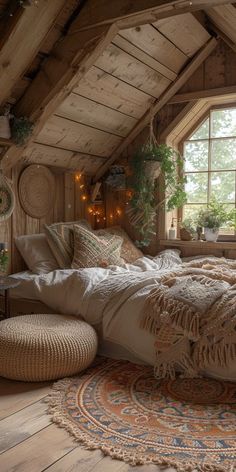 an attic bedroom with wooden walls and flooring is furnished with natural materials such as woven rugs, pillows and blankets